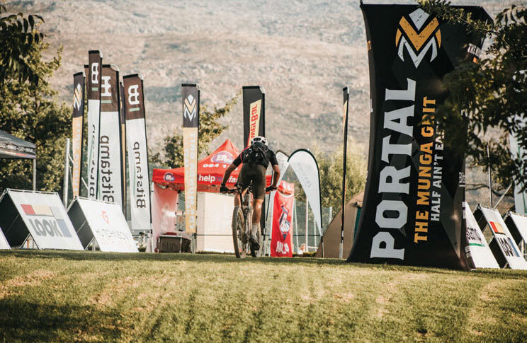 Tall branded yellow and black fabric tower pop up banner with a man cycling fast beside it