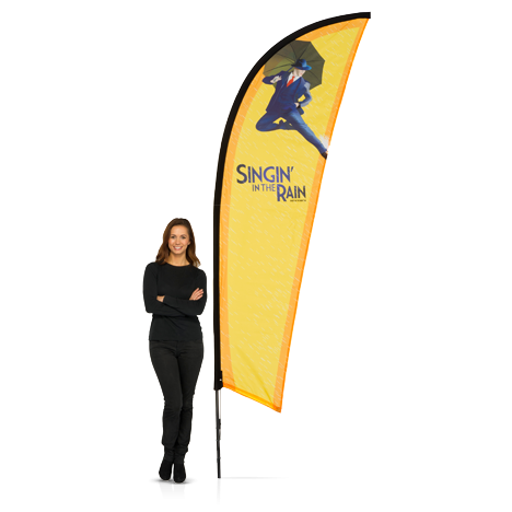 Woman wearing black standing next to large yellow branded pop-out Finn flag banner