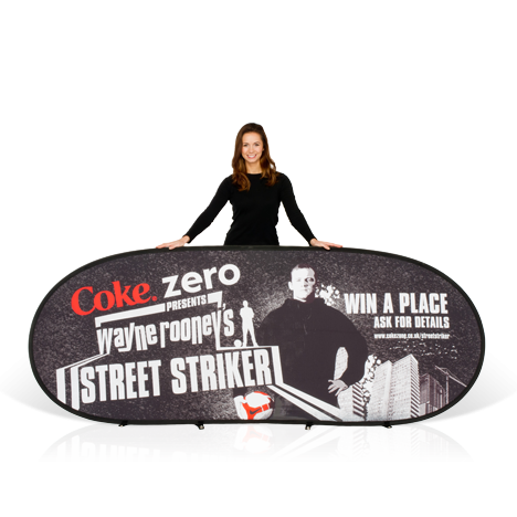 Female model wearing black, holding a branded horizontal pop-up banner advertising Coke Zero