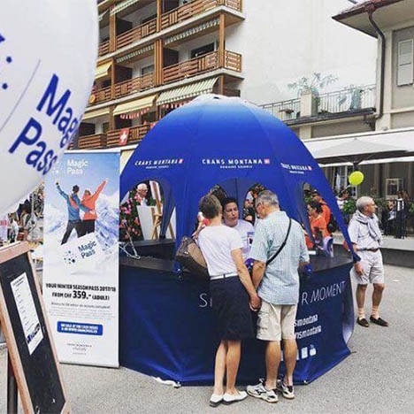 Blue branded pop-up kiosk outdoors at Crans Monata Event